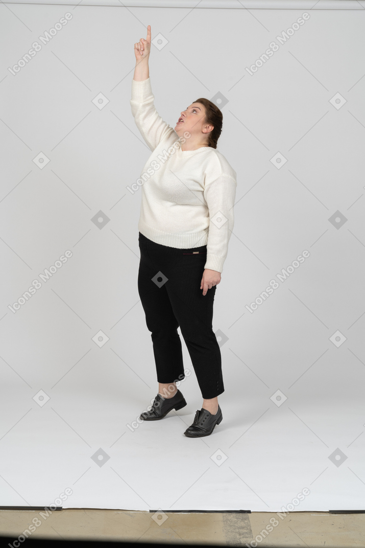 Front view of a plus size woman in casual clothes standing with raised arm