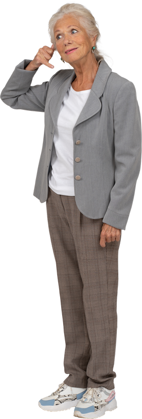 Vista lateral de una anciana en traje mostrando gesto de llamada telefónica