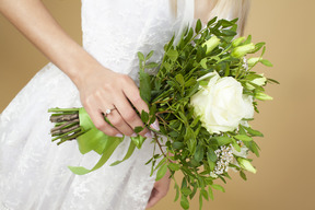 Sposa con un anello su una mano che tiene il bouquet da sposa