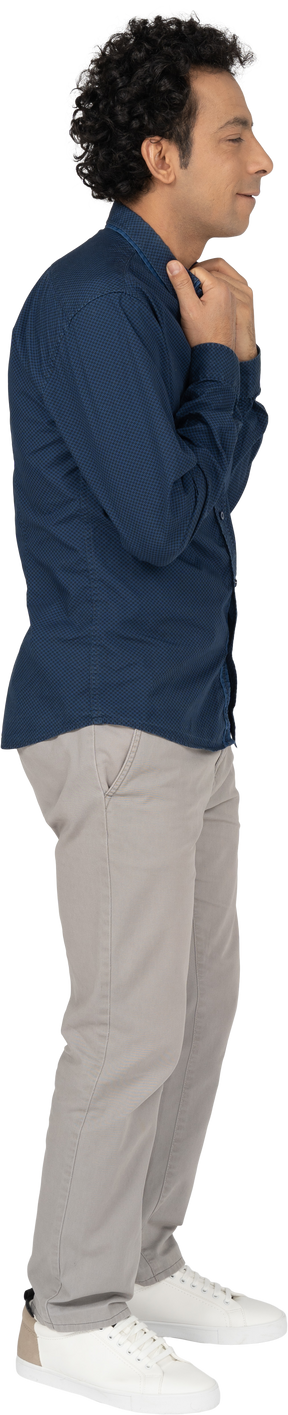 Vista lateral de um homem com roupas casuais tocando o colarinho da camisa