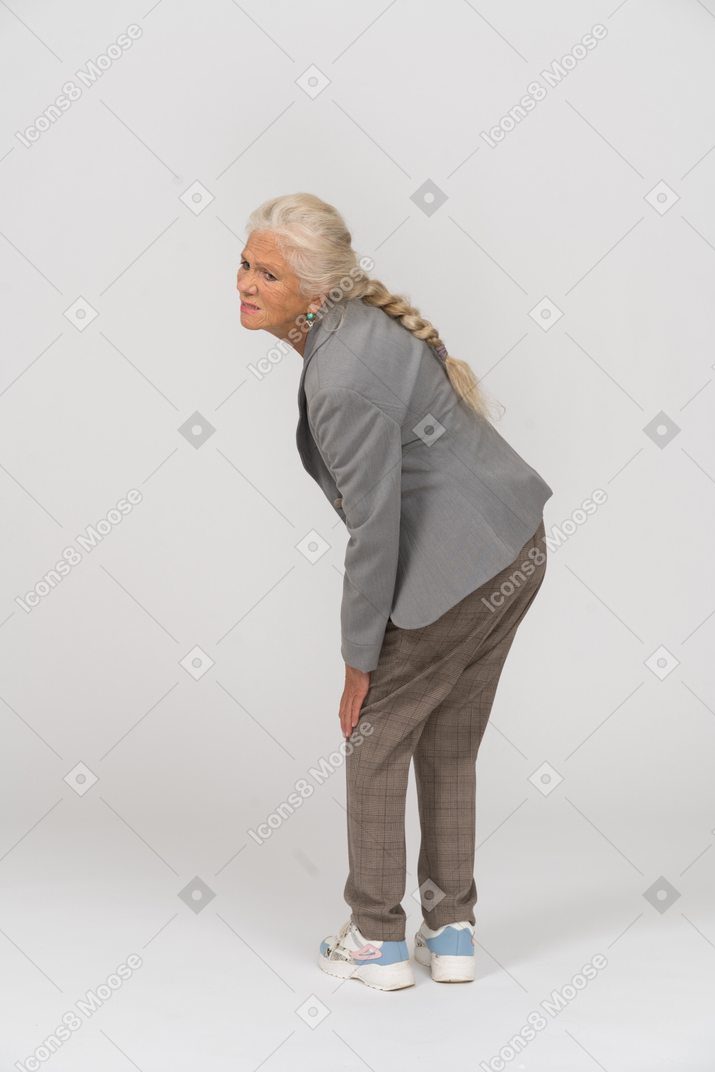 Side view of an old lady in suit touching her hurting knee
