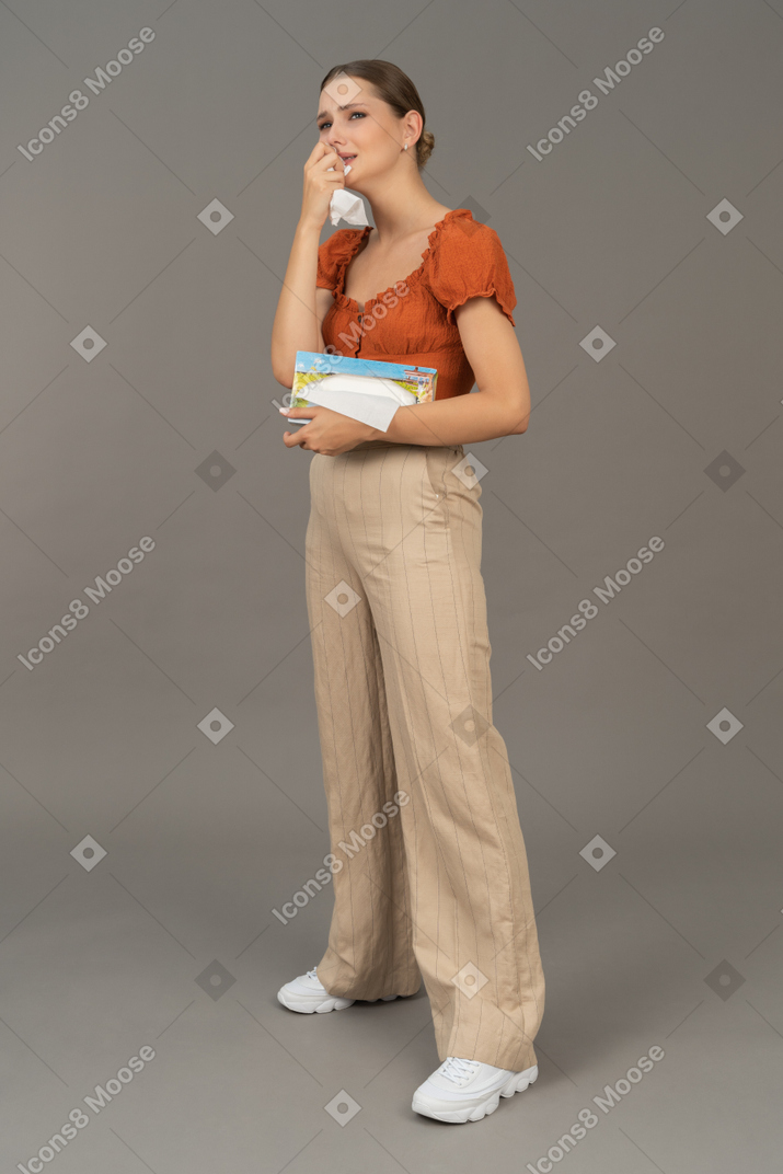Vista di tre quarti di una giovane donna che piange con un fazzoletto in mano