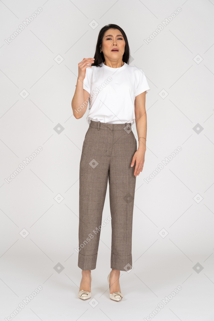 Front view of a sneezing young lady in breeches and t-shirt raising hand