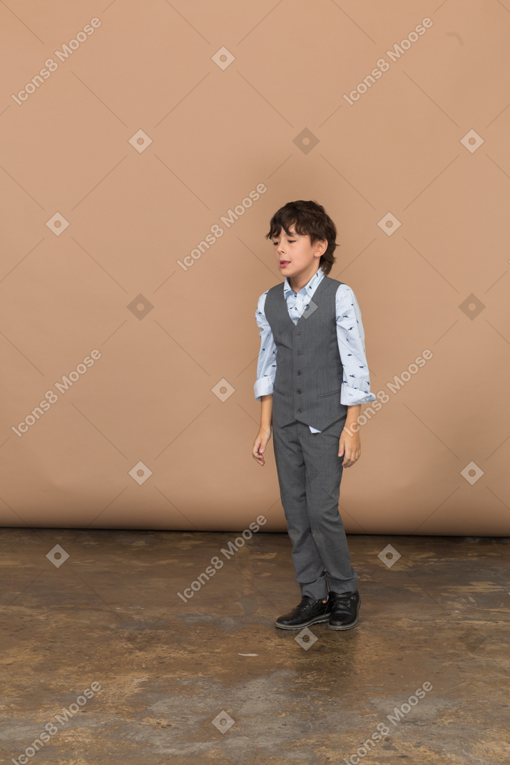 Vista frontal de un niño en traje parado quieto