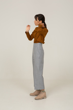 Vista lateral de una joven mujer asiática en calzones y blusa tocando el cuello