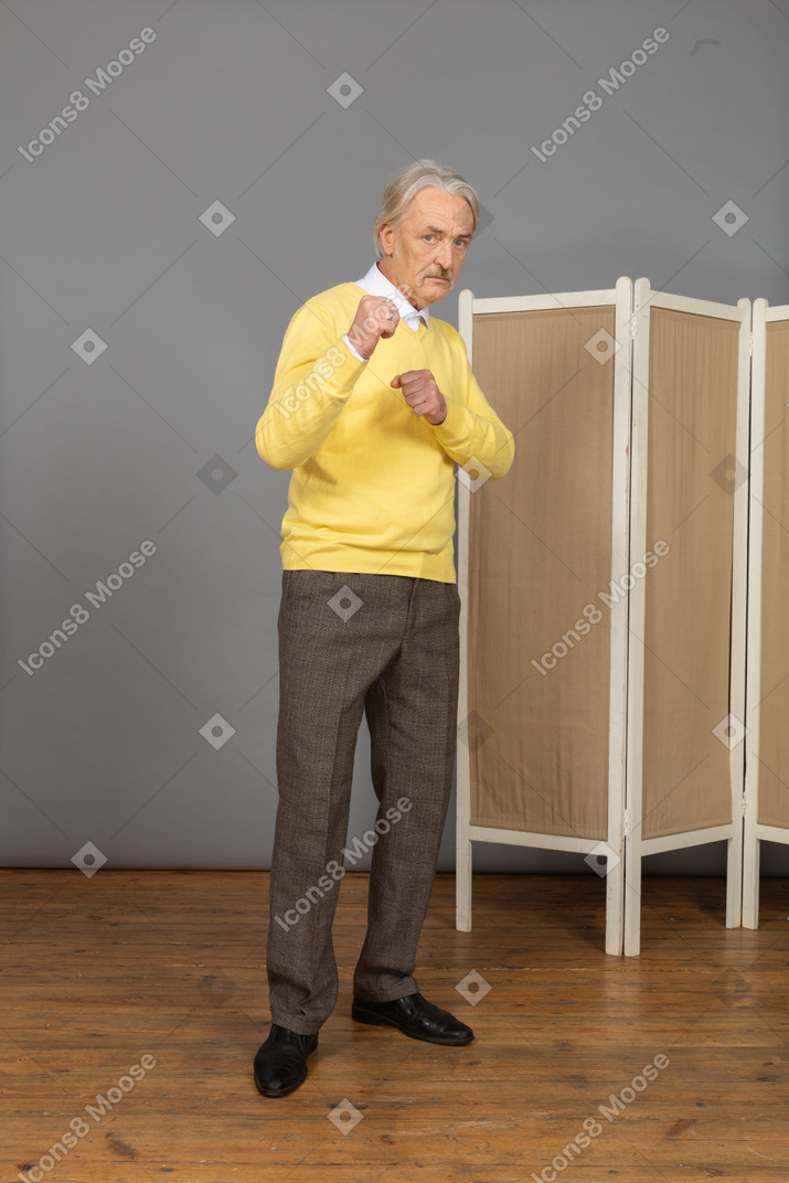 Front view of an old man clenching fists ready to defend
