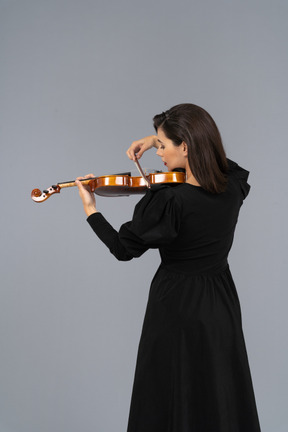 Close-up de uma jovem de vestido preto tocando violino