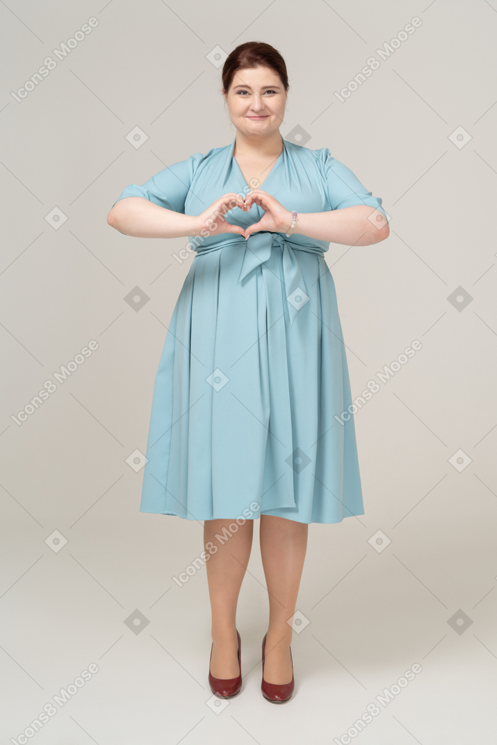 Front view of a woman in blue dress showing heart gesture