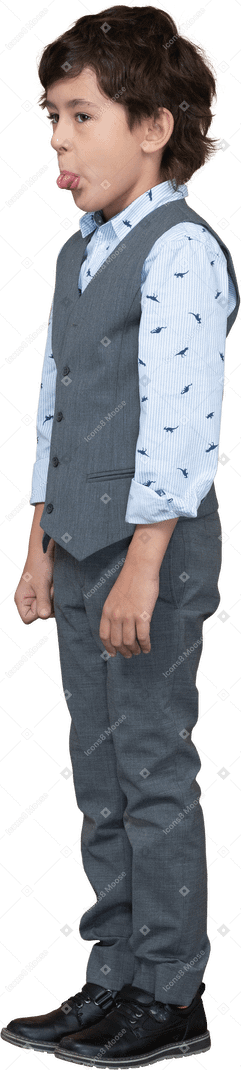 Side view of a cute boy in grey suit showing tongue