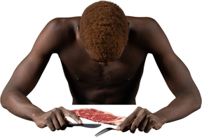 肉の近くに座っている引きこもりの若いアフロ男の正面図