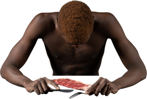 Front view of a withdrawn young afro man sitting near meat