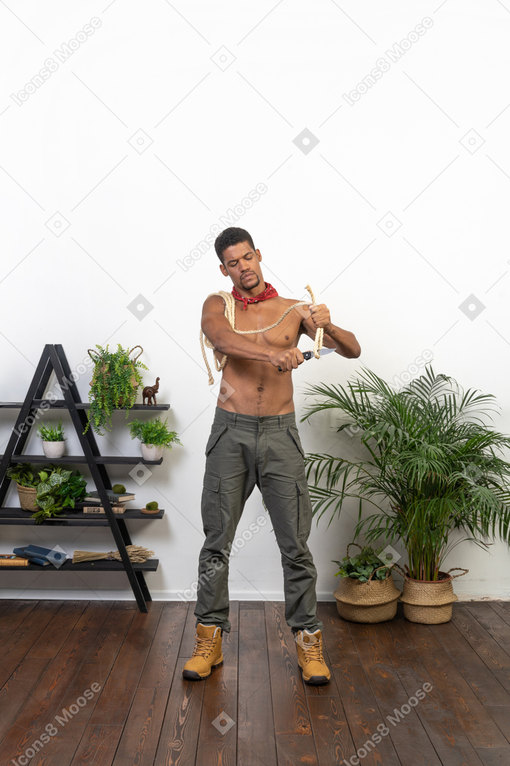 Athletic young man cutting off rope with a blade
