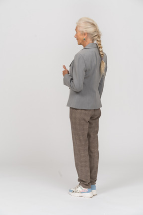 Rear view of an old lady in suit showing thumb up