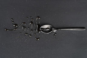 Metallteelöffel mit flüssigkeit auf dem schwarz