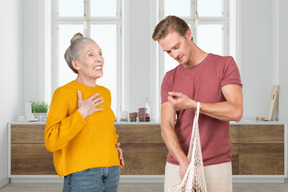 Old woman laughing and standing next to a man with reusable bag