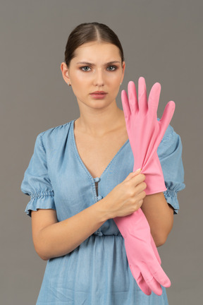 Close-up of a beautiful young woman putting on latex gloves while looking annoyed