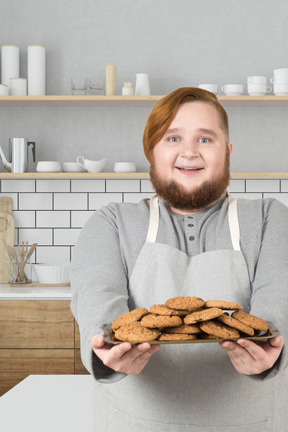 A man holding a plate of cookies in a kitchen
