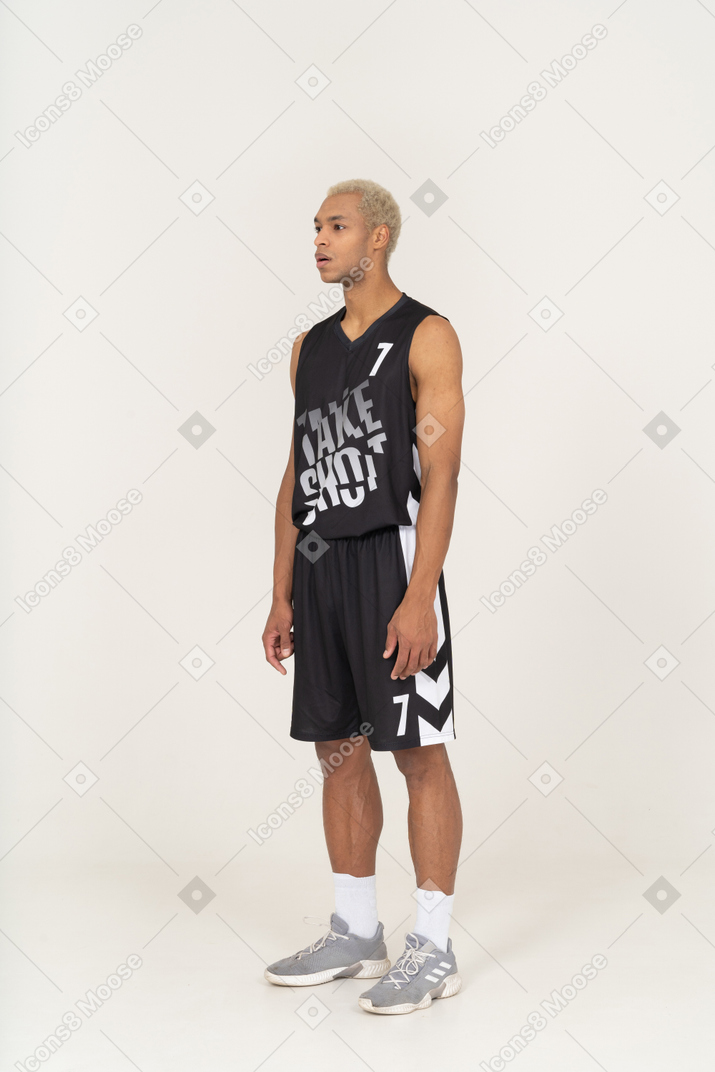 Vista de tres cuartos de un joven jugador de baloncesto masculino parado con la boca abierta