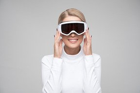 Mulher loira alegre ajustando óculos de esqui