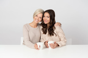 Young women embracing and drinking coffee