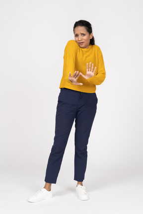 Vista frontal de uma garota assustada em roupas casuais mostrando um gesto de pare
