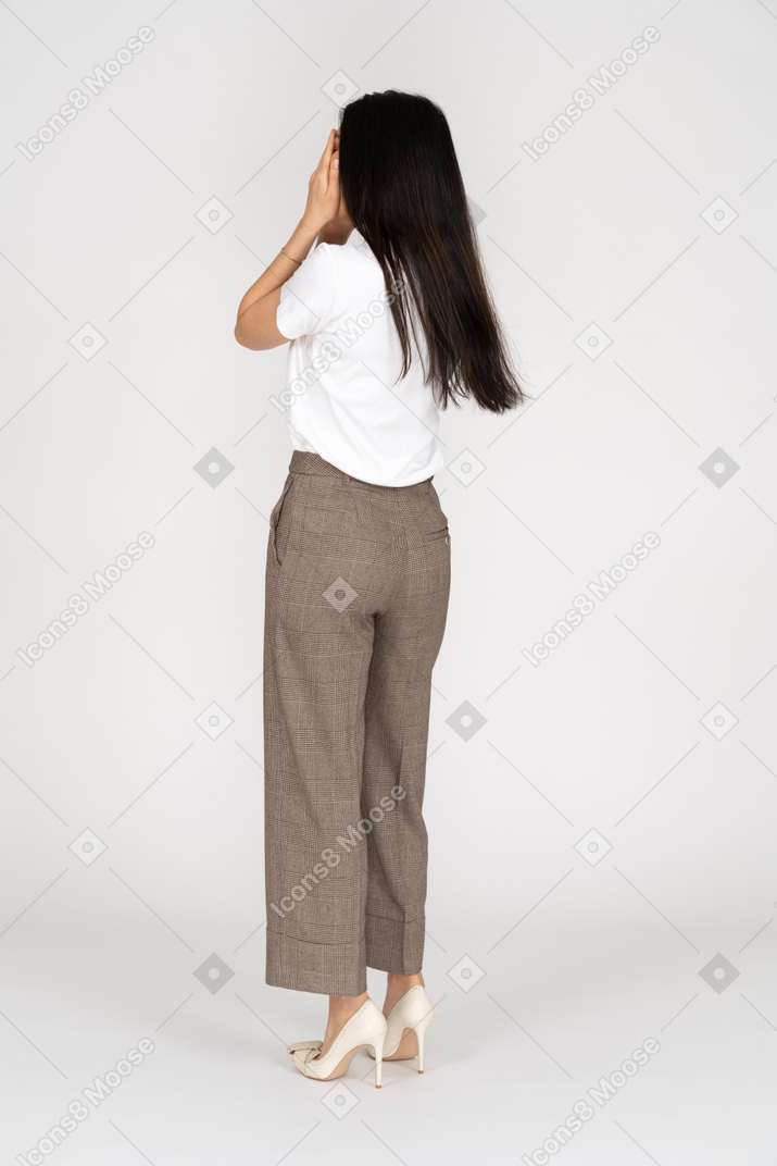 Three-quarter back view of a young lady in breeches and t-shirt hiding her face