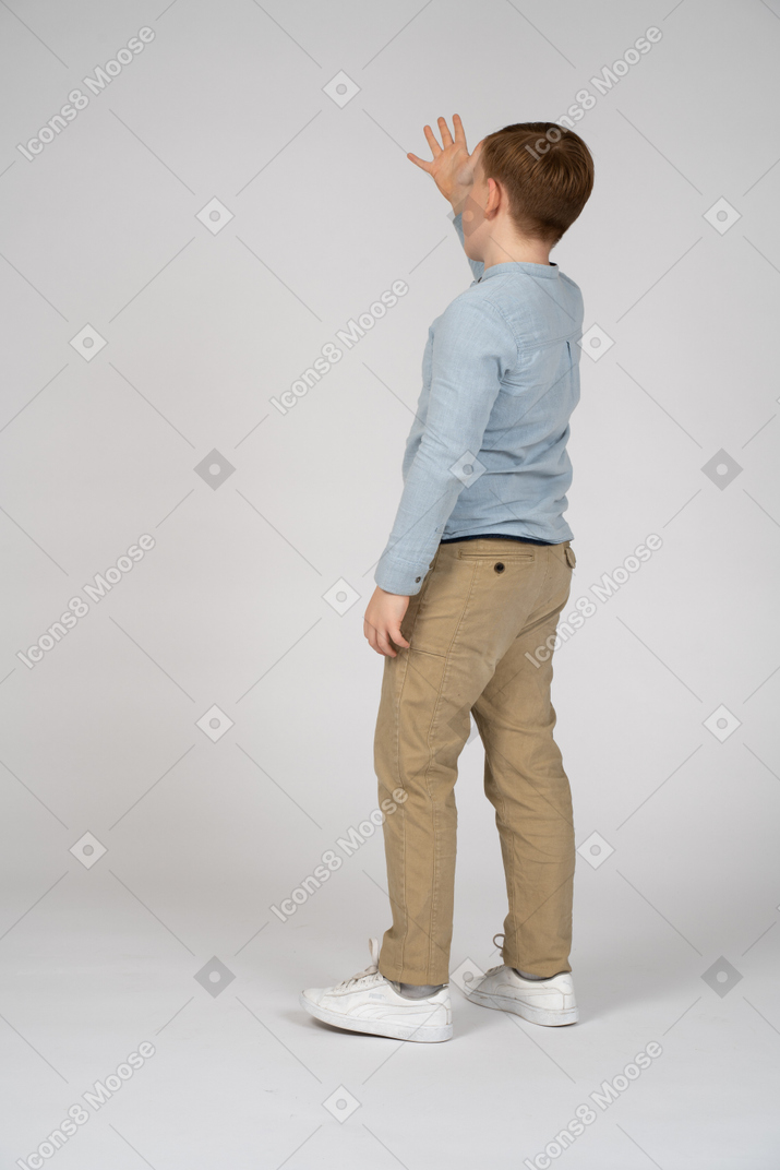 Young boy standing and raising his hand