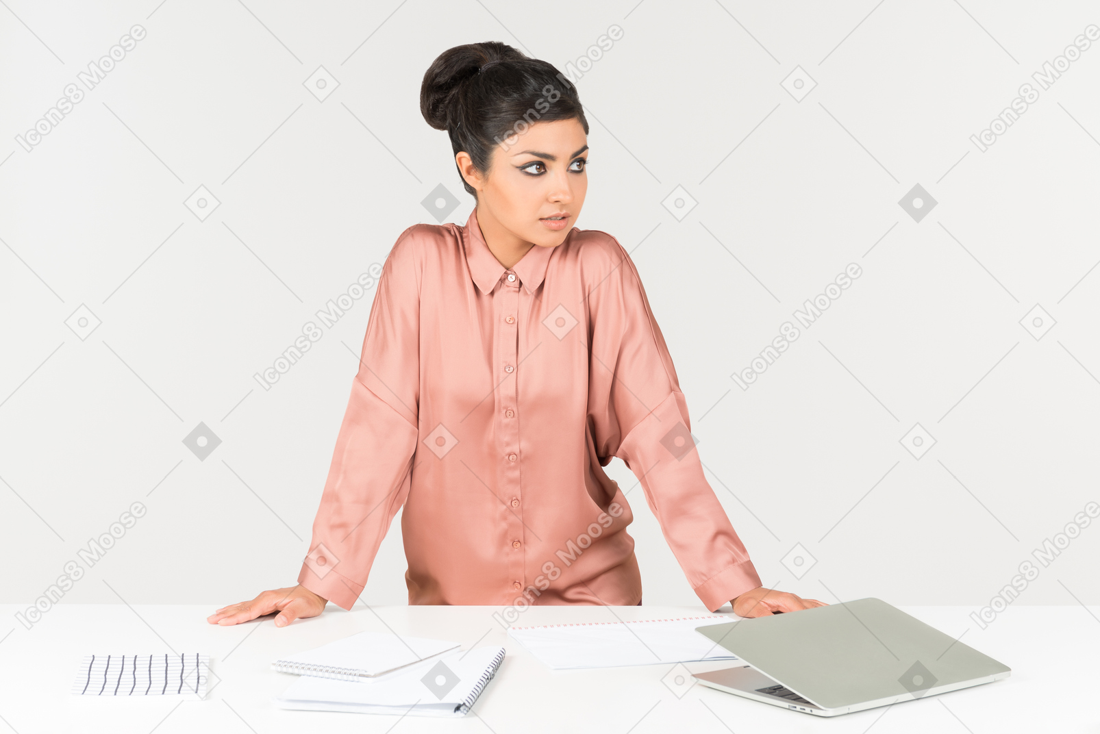 Young indian office worker standing near the table with laptop on it