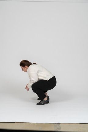 Side view of a plump woman in casual clothes squatting