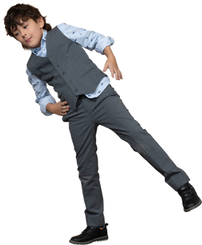一个穿着西装的男孩用一只腿保持平衡，手放在臀部的正面图