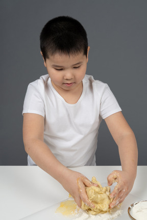 A little boy kneading a dough