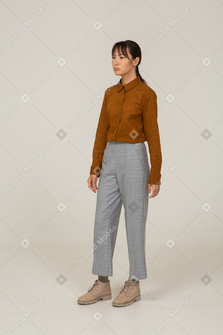 Vista de tres cuartos de una joven asiática desconcertada en calzones y blusa inmóvil