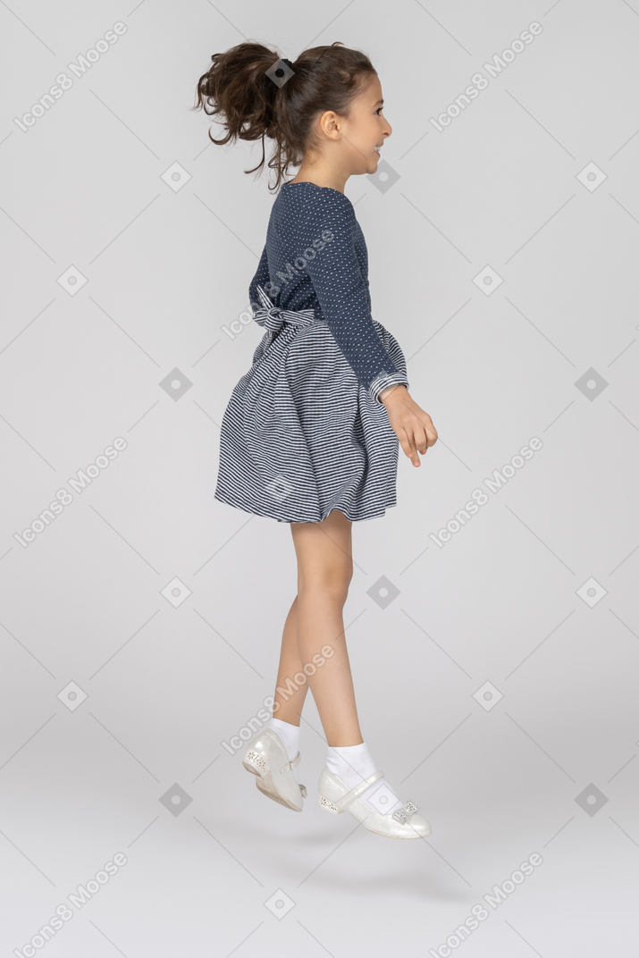 Side view of a girl jumbing high with a smile