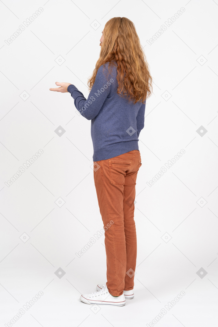 Seitenansicht eines jungen mannes in freizeitkleidung, der mit ausgestreckter hand steht
