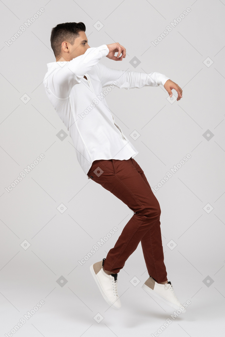 Side view of a young latino man jumping and stumbling