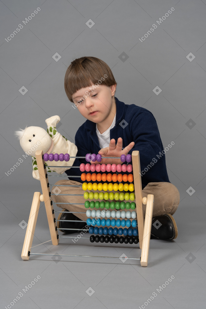 Little boy holding a puppet while using an abacus