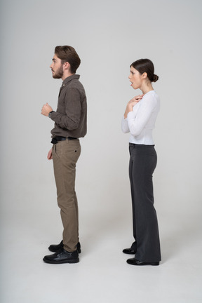 Vista lateral de una pareja joven conmocionada en ropa de oficina