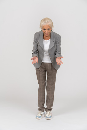 Vista frontal de una anciana en traje agachándose y explicando algo