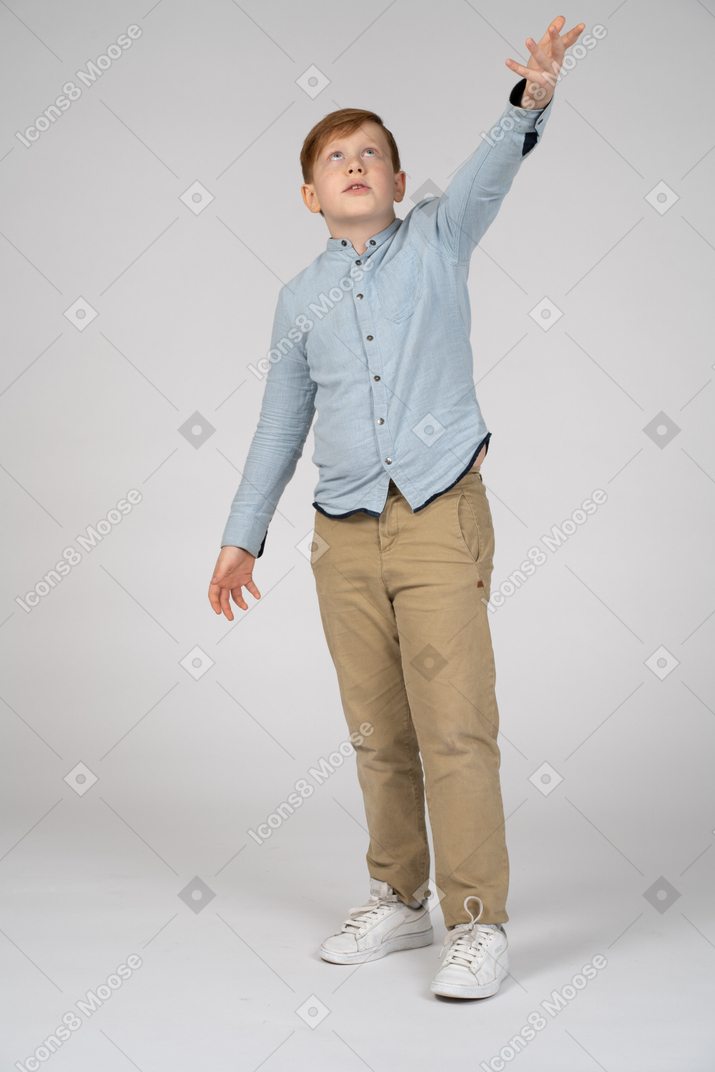 Вид спереди мальчика, указывающего вверх рукой