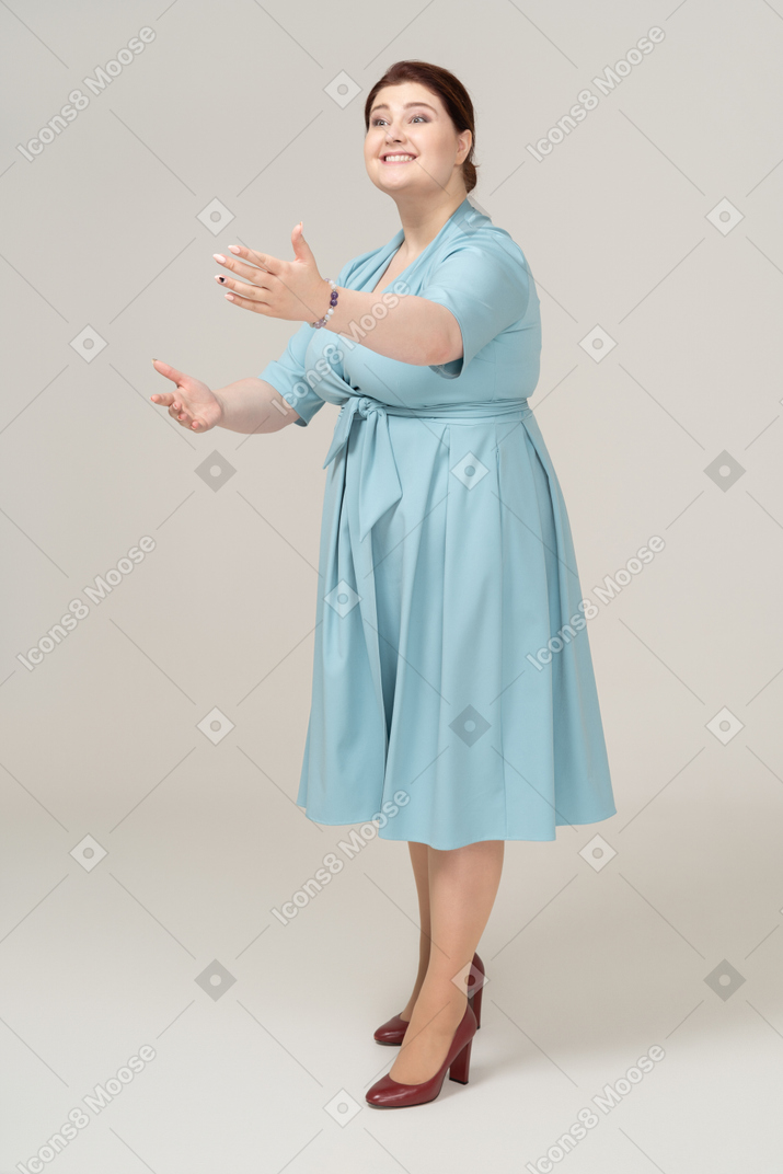 一个穿着蓝色连衣裙的女人的前视图问候某人