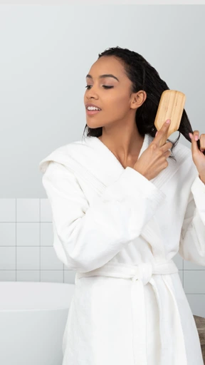 A woman is brushing her hair in the bathroom