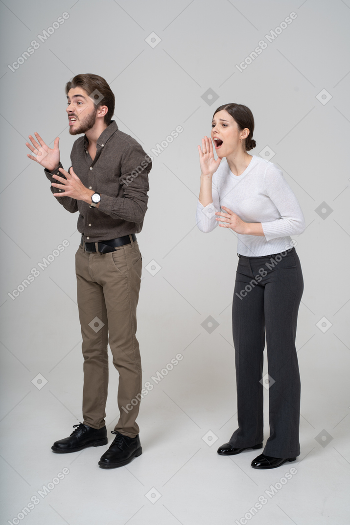 Three-quarter view of an emotional gesticulating young couple in office clothing