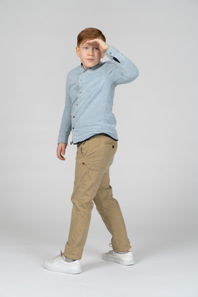 Young boy in blue shirt and khaki pants searching for something