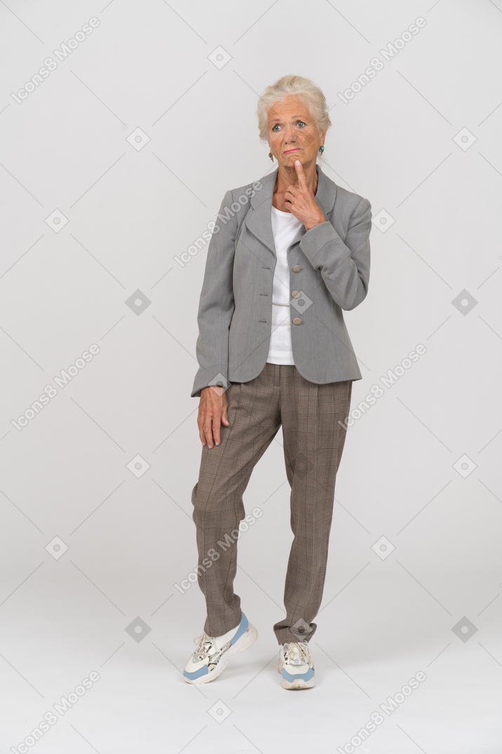 Вид спереди задумчивой старушки в костюме, касающейся ее подбородка