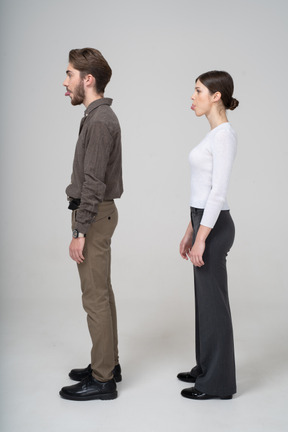 Side view of a young couple in office clothing showing tongue