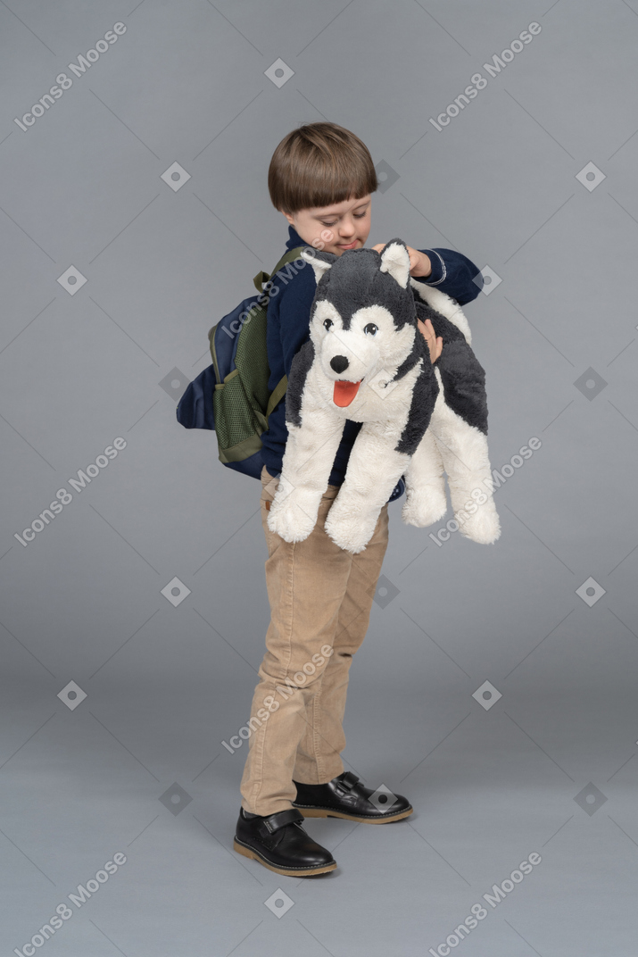 Little boy with a backpack holding a dog plushie