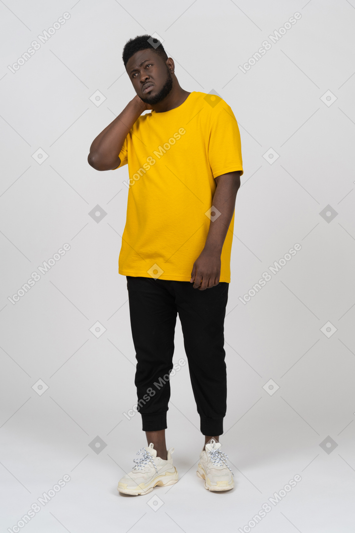 Front view of a dark-skinned man in yellow t-shirt touching his neck