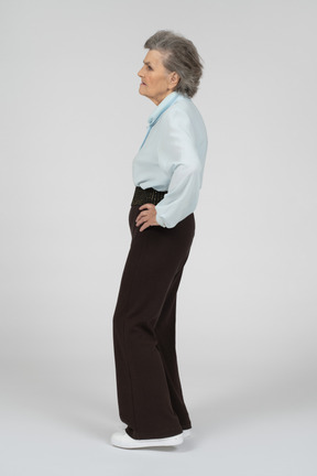 Vista lateral de una anciana con una mano en la cadera que parece decepcionada