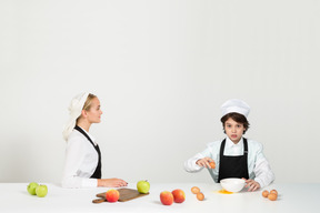 Un adolescente atractivo aprendiendo a cocinar bajo la supervisión de su madre.