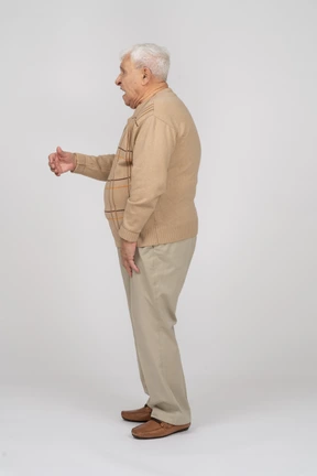 Side view of an old man in casual clothes explaining something